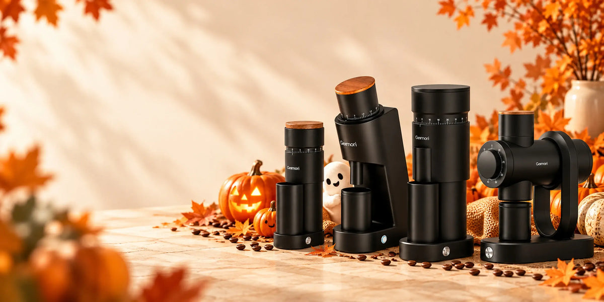 Four black coffee grinders arranged on a tabletop with autumn leaves, pumpkins, and warm sunlight in the background.slider_item_re4TfX